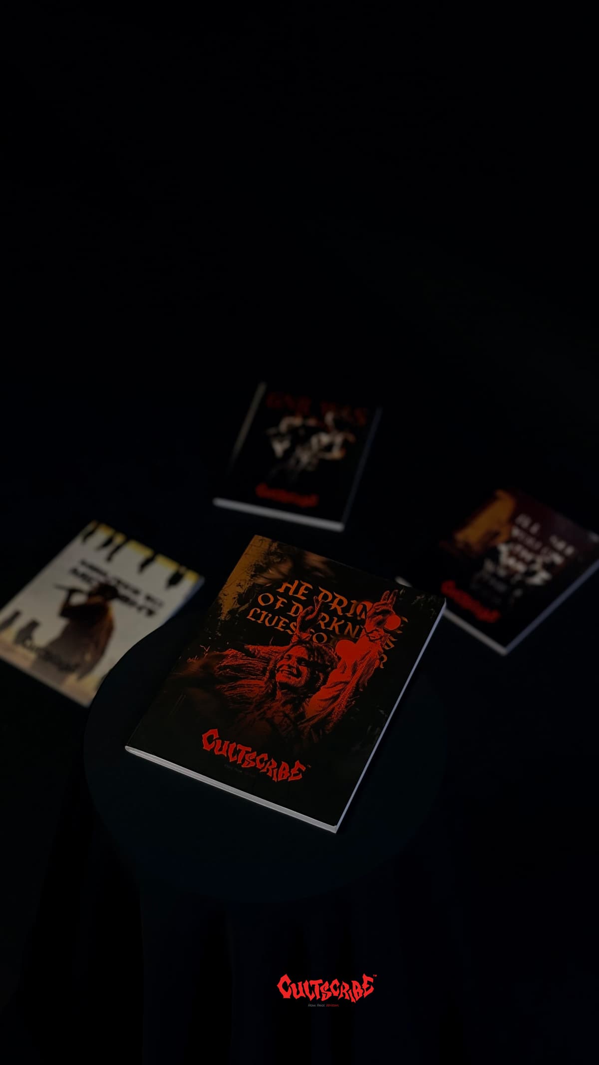 CultScribe product showcase — Prince of Darkness notebook on a black pedestal with blurred titles in the background.