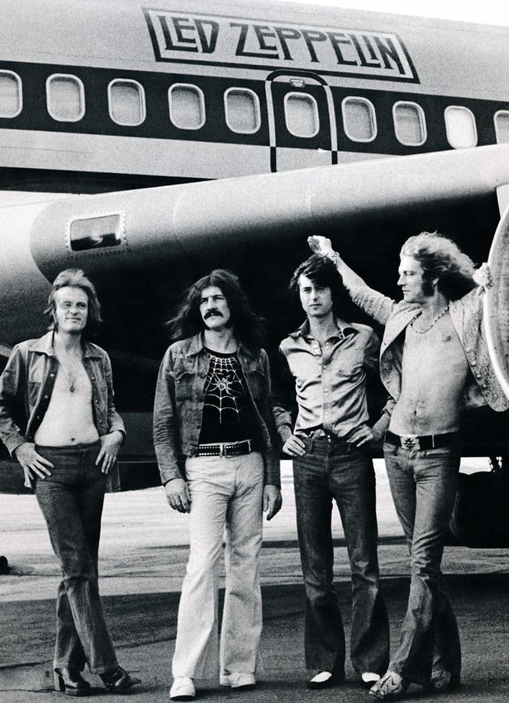 Led Zeppelin with The Starship tour plane — band portrait on the airfield, black and white.