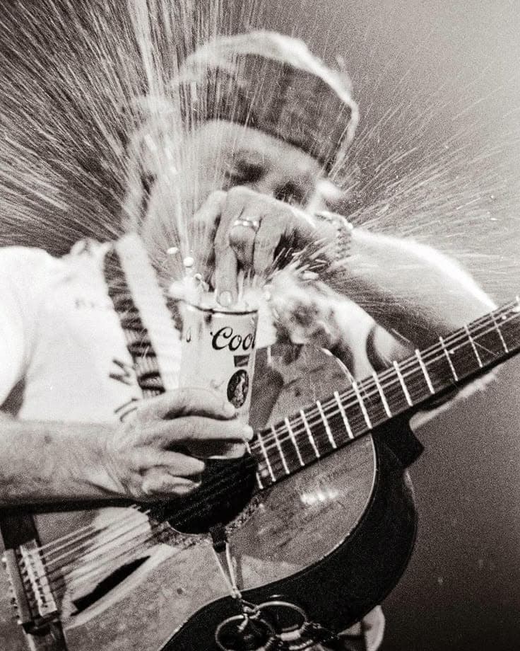 Willie Nelson on stage with Trigger and a spraying beer can — black and white.